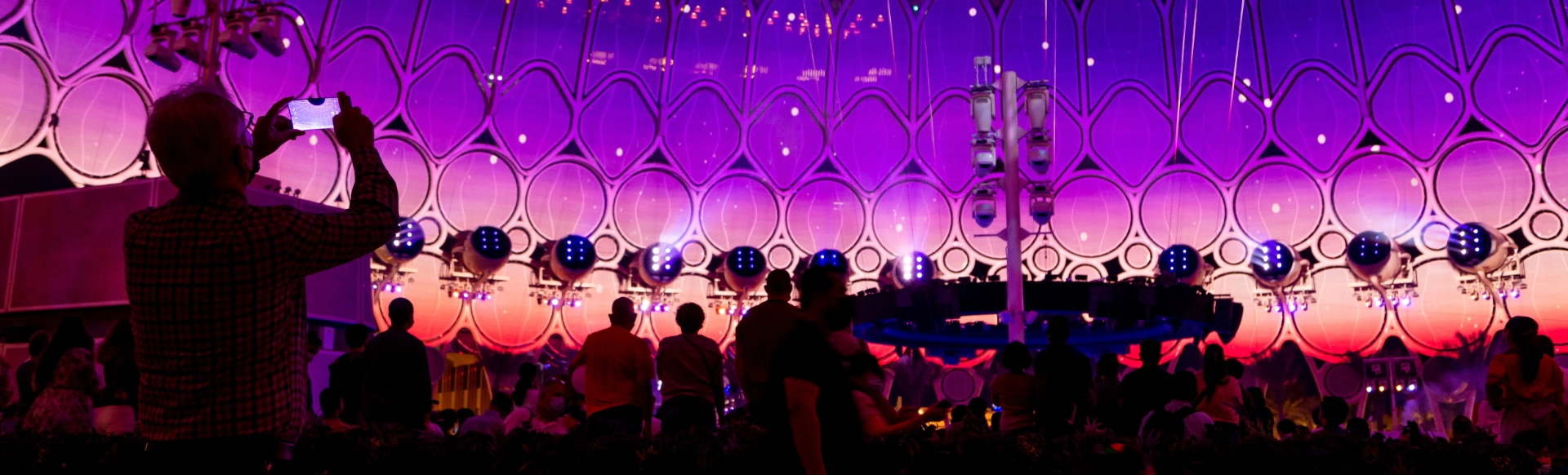 Large crowd at a UAE outdoor event watching a building projection mapping show, phones raised